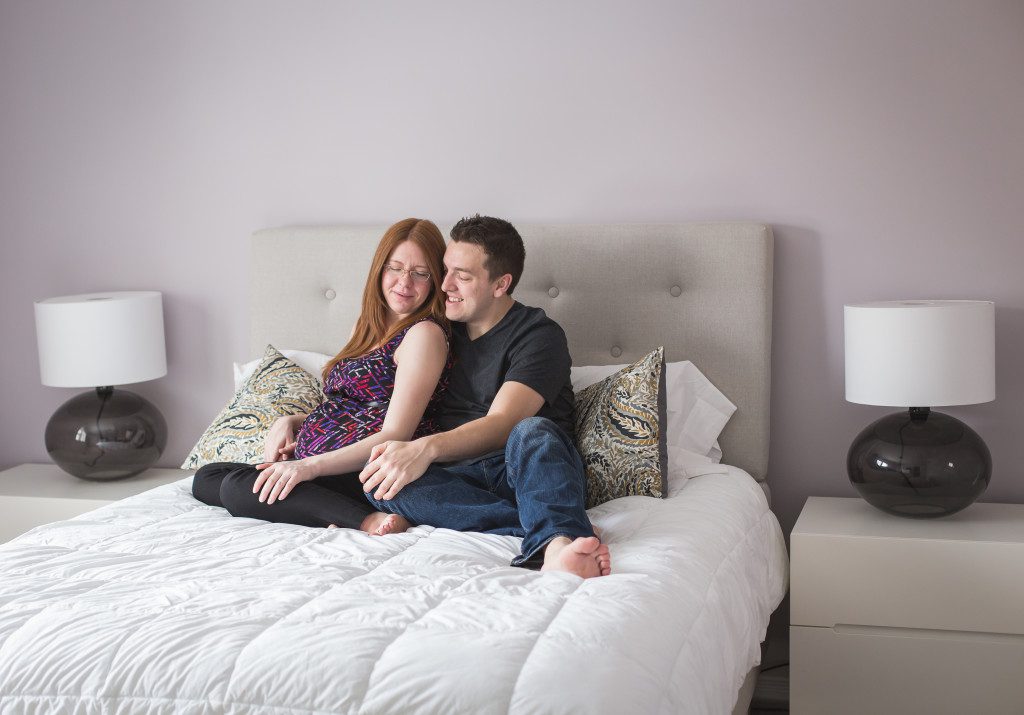 expecting couple snuggling on bed