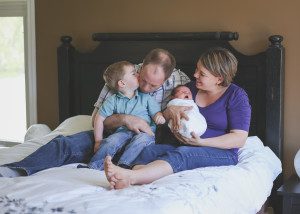 family with new baby on master bedroom