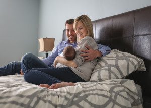 new family holding daughter on bed