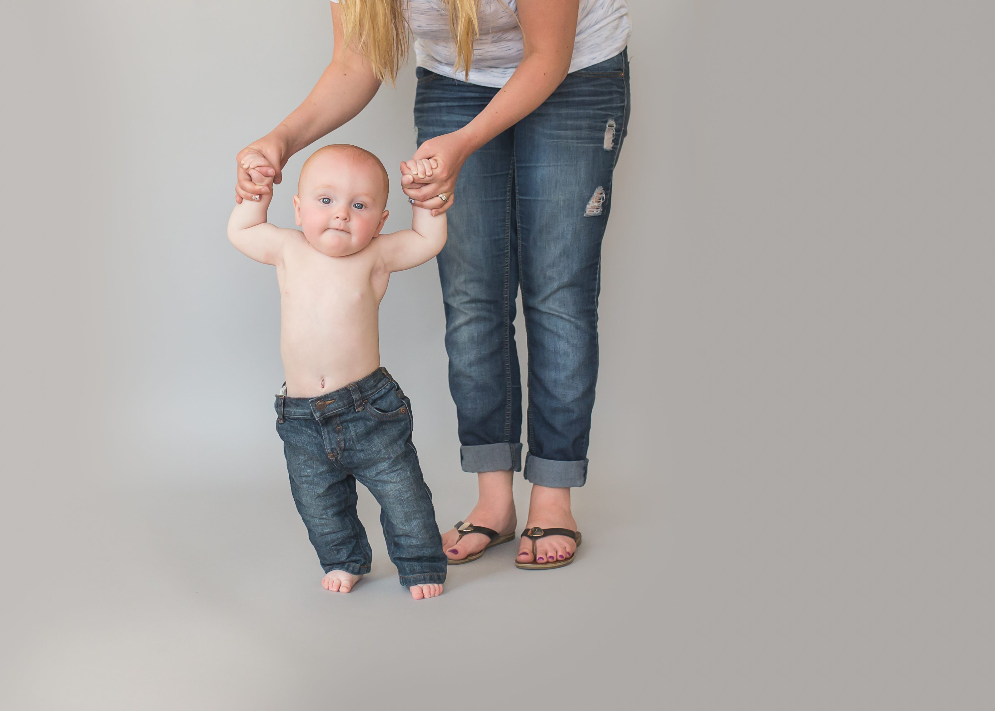 red haired baby boy standing with help from mom during baby photos