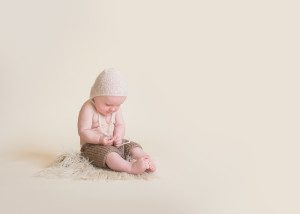 baby boy in bonnet on cream backdrop set for his simply baby session
