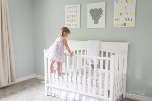 sister looking in crib at brother