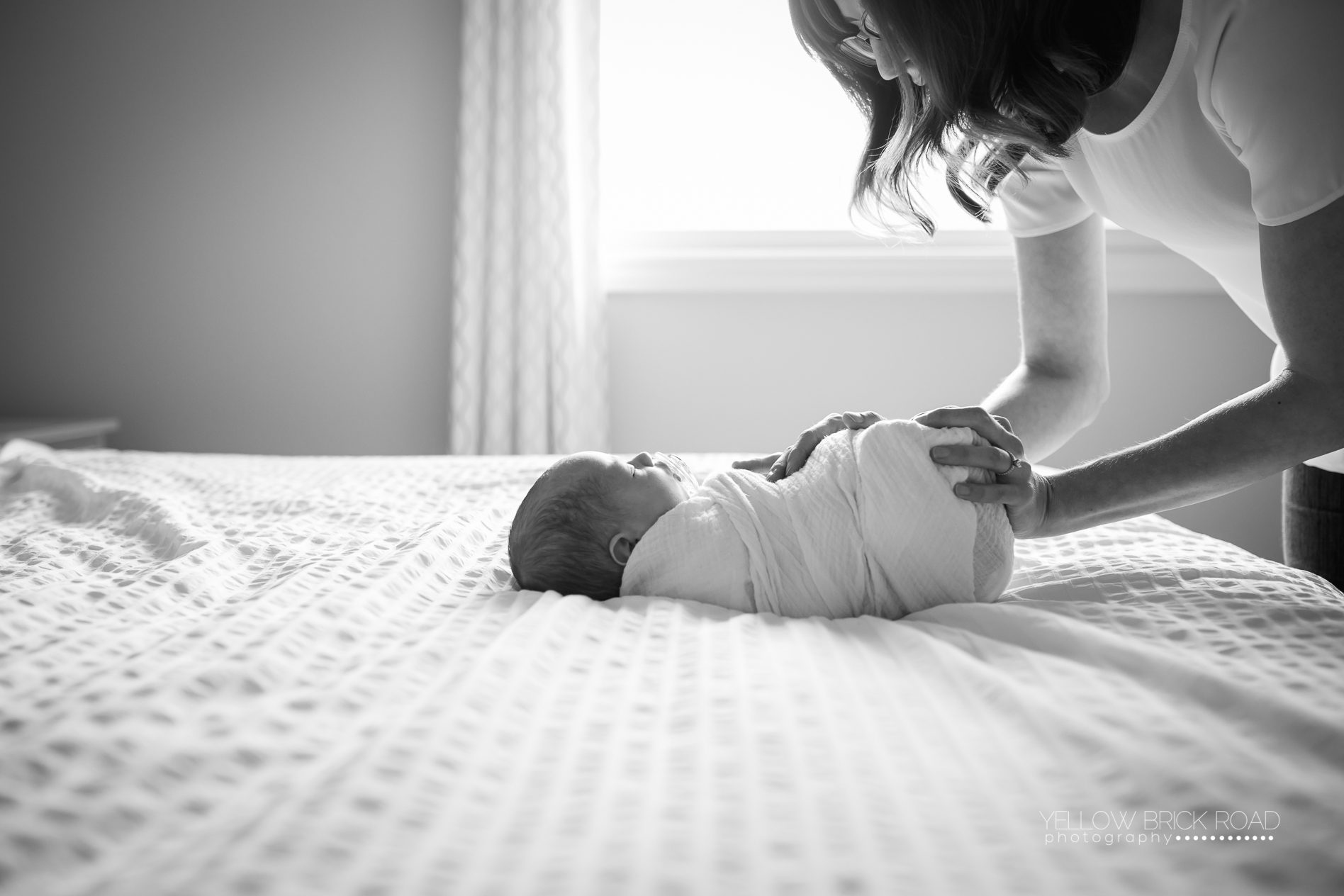 newborn baby wrapped in swaddle being consoled by his mom