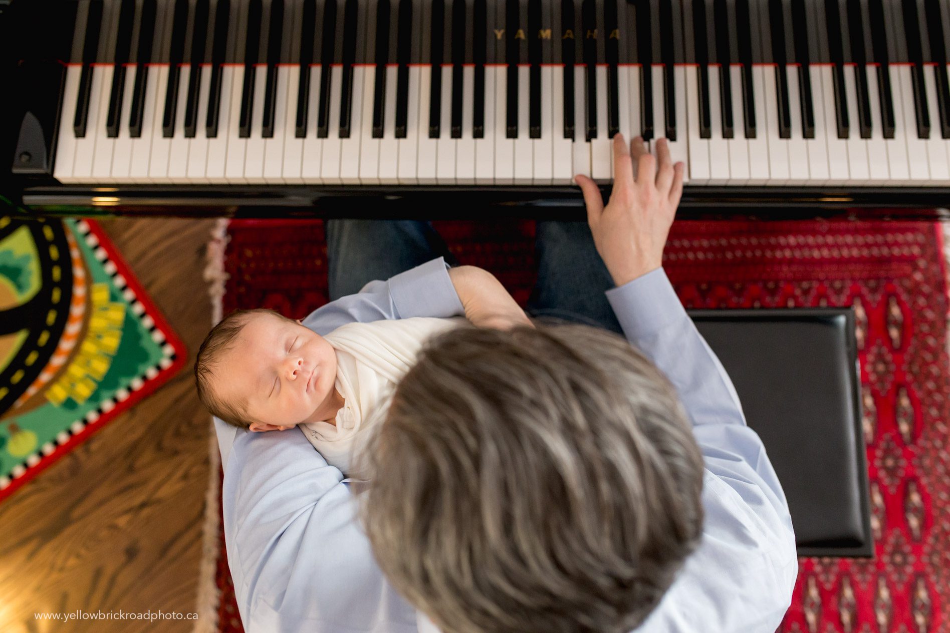 Toronto Newborn Lifestyle Photographer Dad playing piano with newborn