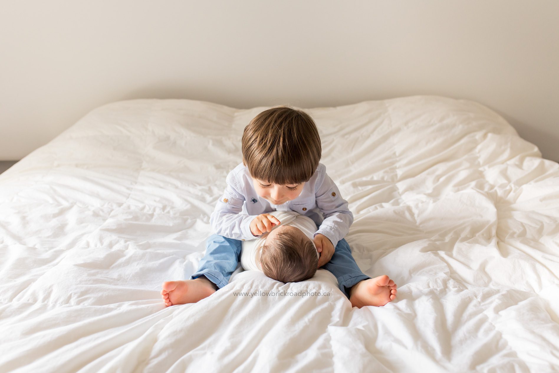 Toronto Newborn Lifestyle Photographer bib brother looking at little brother on bed