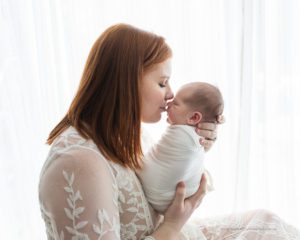 mom kissing newborn